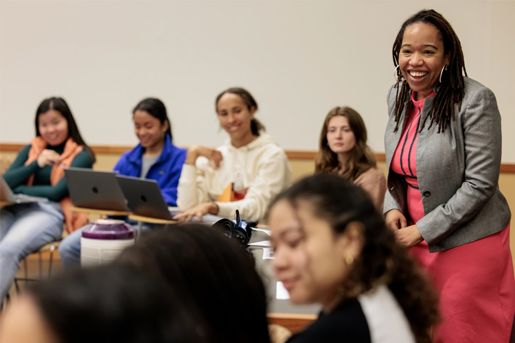 A professor in a classroom smiling